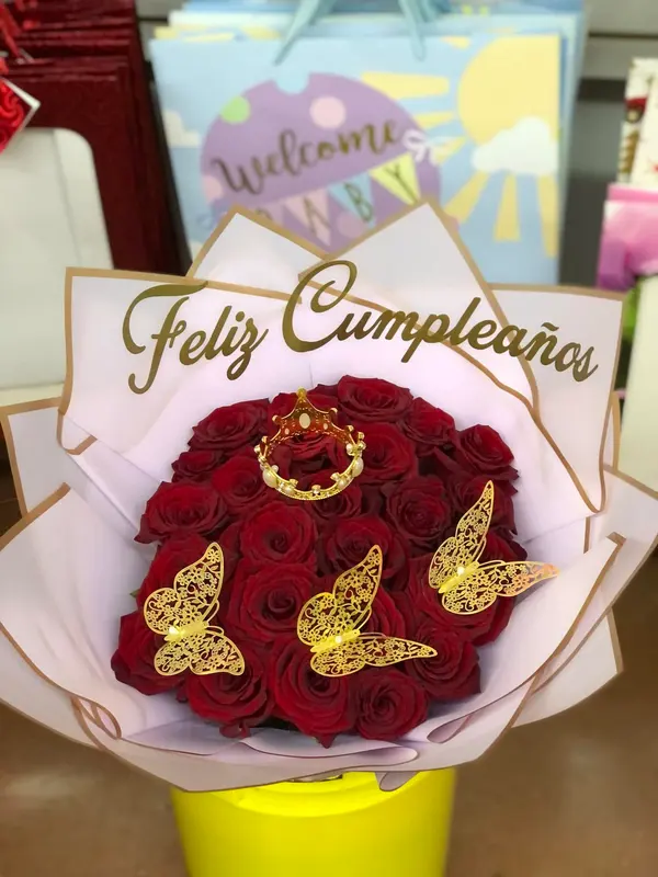 Ramo de rosas rojas con mariposas doradas y banda 'Feliz Cumpleaños' en papel rosa
