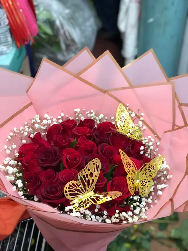 Ramo de rosas rojas con nube y mariposas doradas en papel rosa